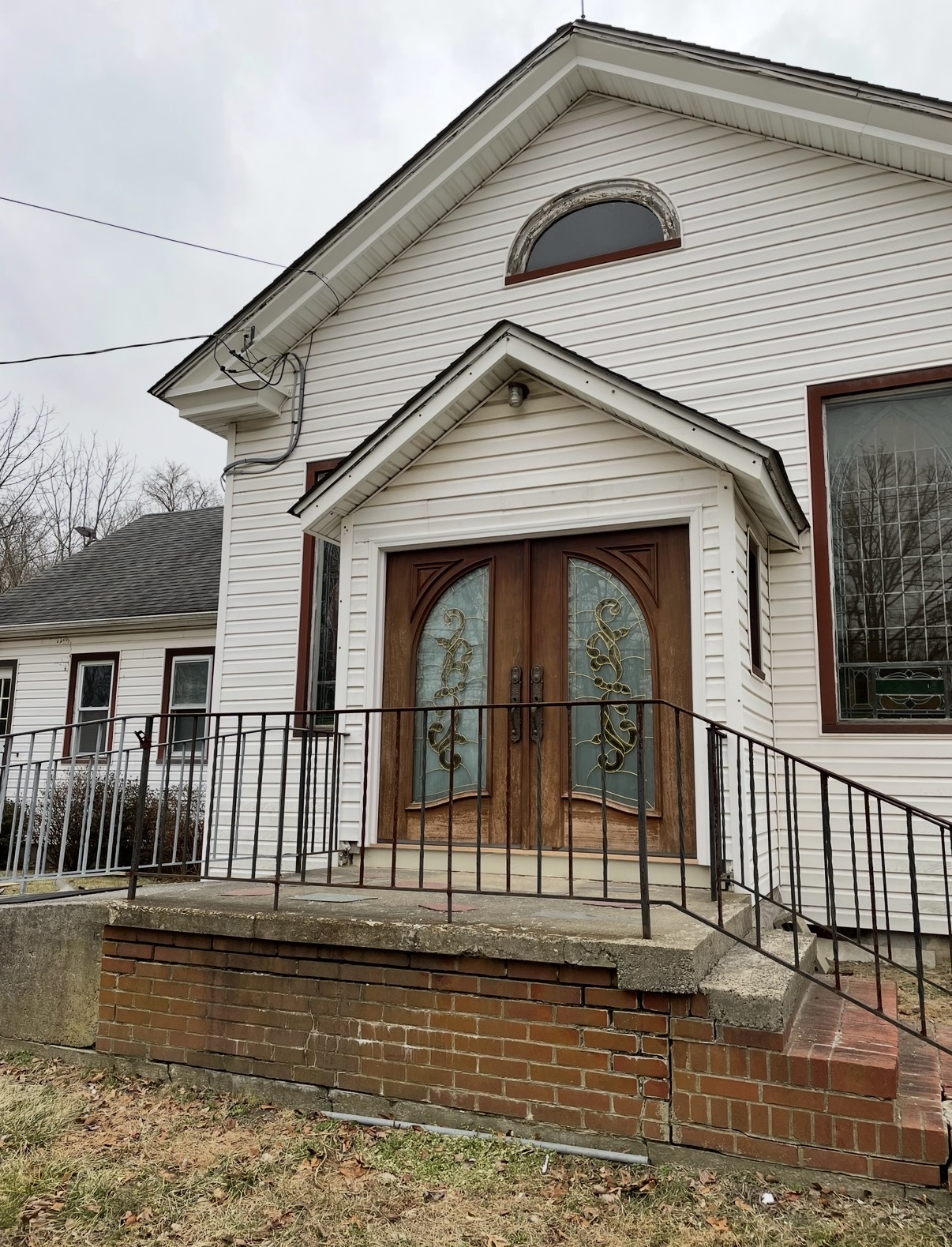 Before — historic double doors with weathered finish and original leaded glass at the front of a country church