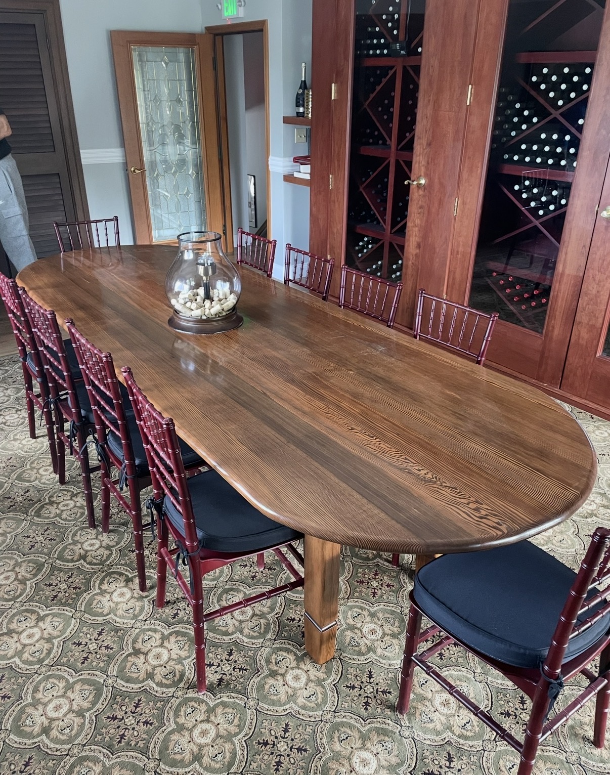 Finished oval dining table installed in a private wine room with chiavari chairs
