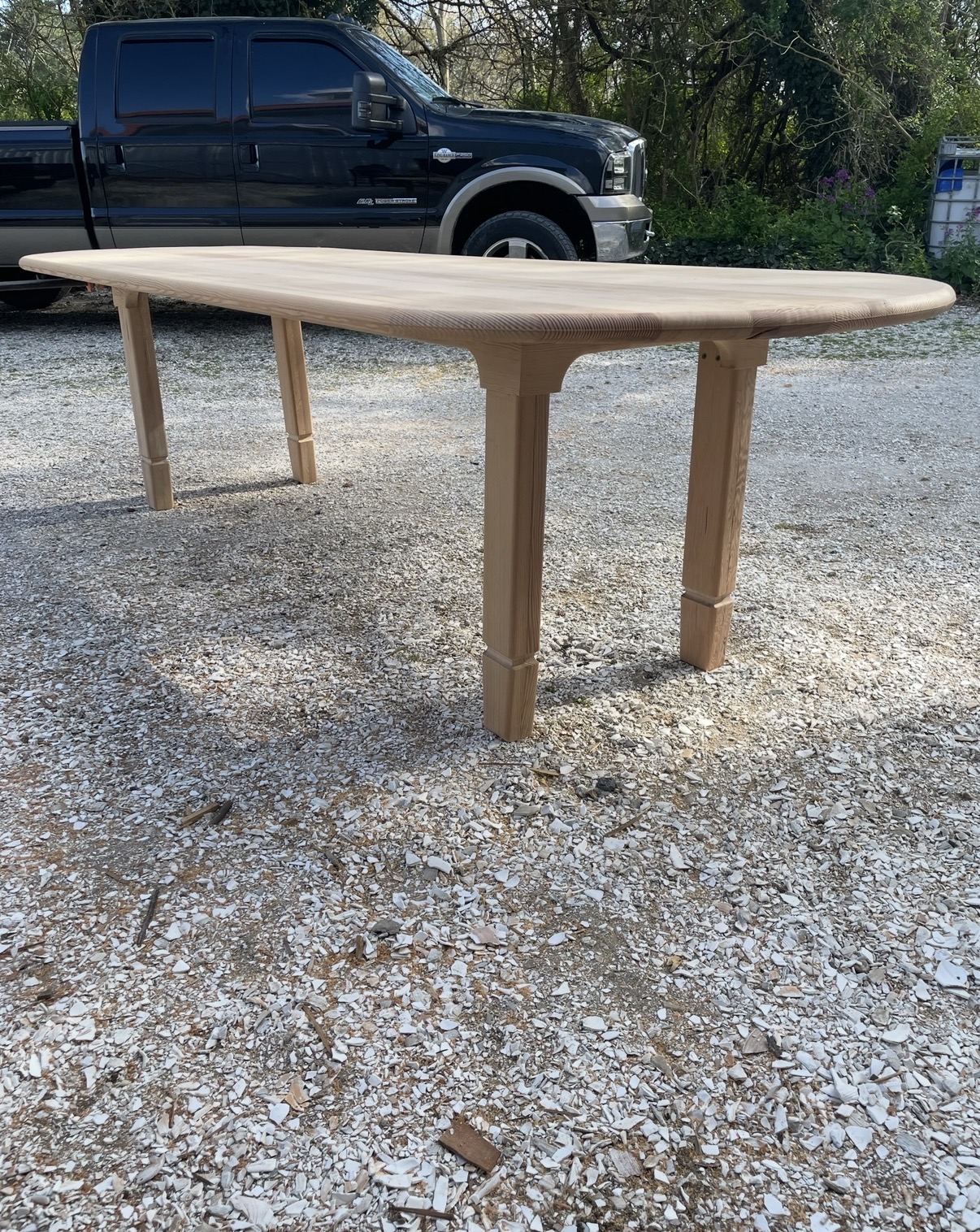Side view of the raw table assembled in the yard, showing turned legs and shaped apron