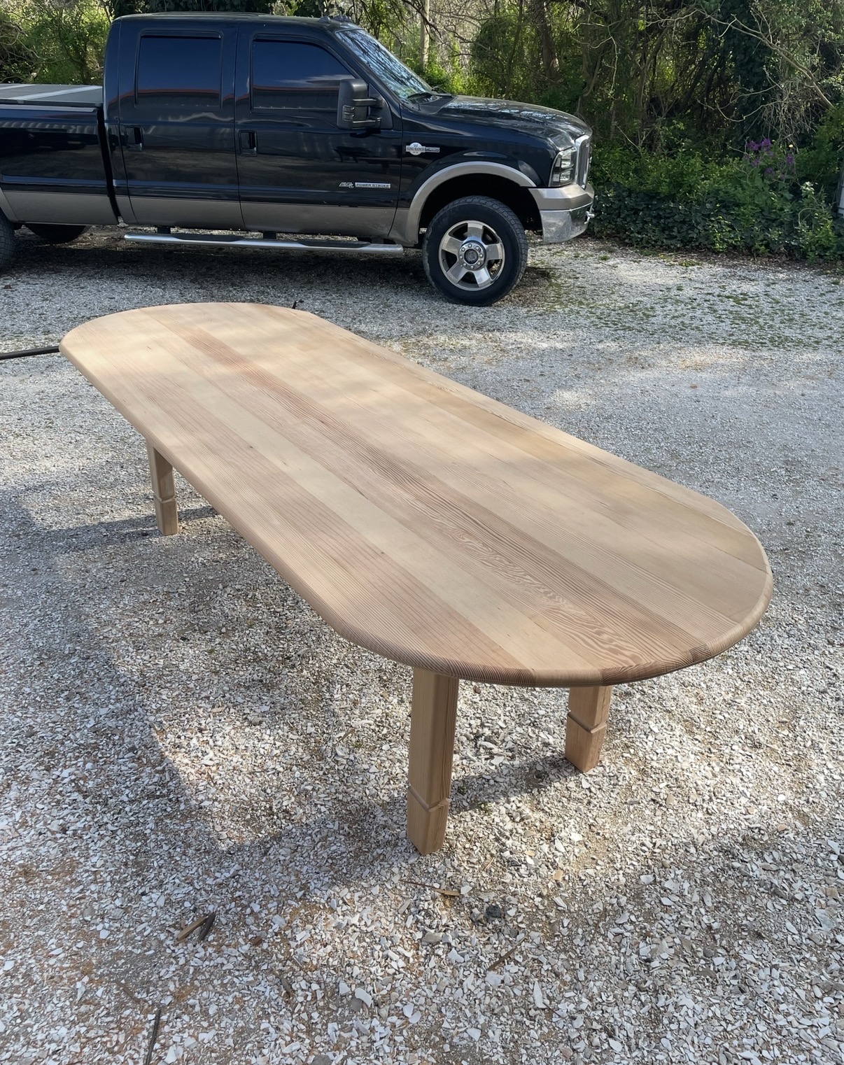 Raw, unfinished oval table top showing book-matched solid pine boards before staining